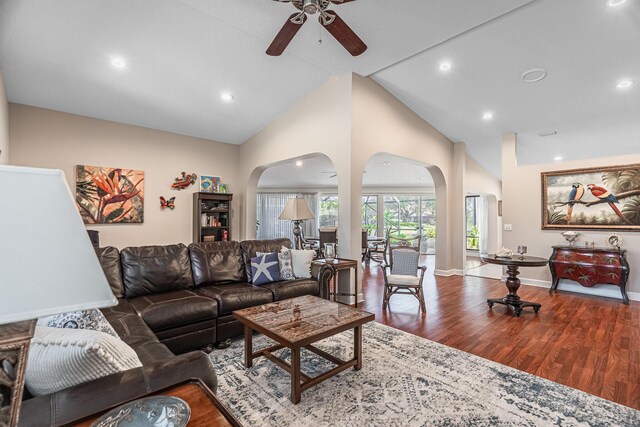 living room with high vaulted ceiling, a ceiling fan, wood finished floors, arched walkways, and baseboards