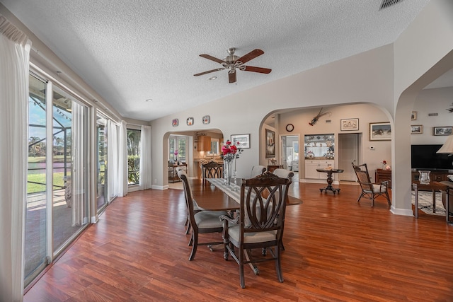 dining room featuring hardwood / wood-style floors, a textured ceiling, vaulted ceiling, and ceiling fan