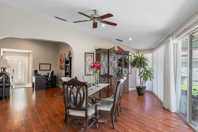 dining room with dark hardwood / wood-style floors, vaulted ceiling, and a textured ceiling