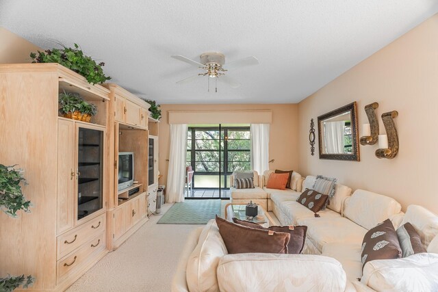 living room with ceiling fan with notable chandelier, carpet floors, and a textured ceiling