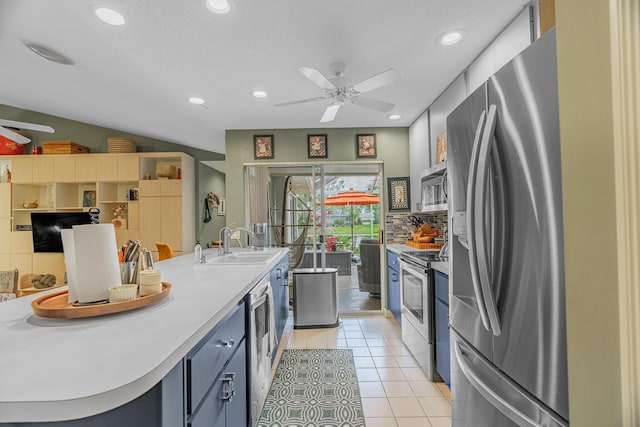 kitchen featuring appliances with stainless steel finishes, sink, backsplash, light tile patterned floors, and blue cabinetry