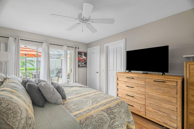 bedroom featuring ceiling fan, wood-type flooring, a textured ceiling, and access to outside