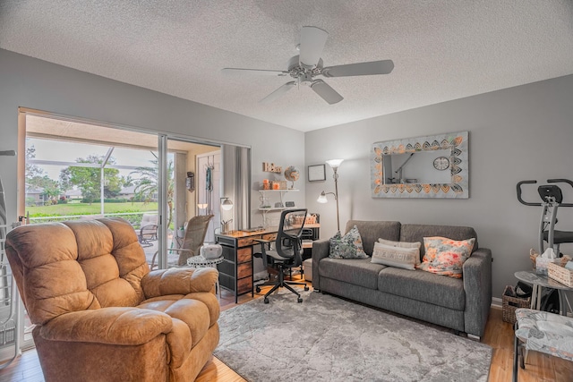 living room featuring ceiling fan, hardwood / wood-style floors, and a textured ceiling