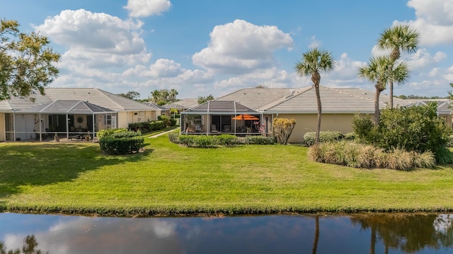 rear view of property with a water view, glass enclosure, and a lawn