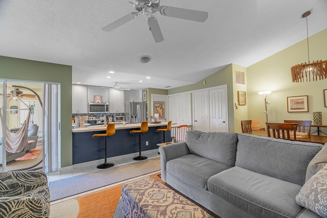 living room featuring lofted ceiling, a textured ceiling, and light tile patterned floors