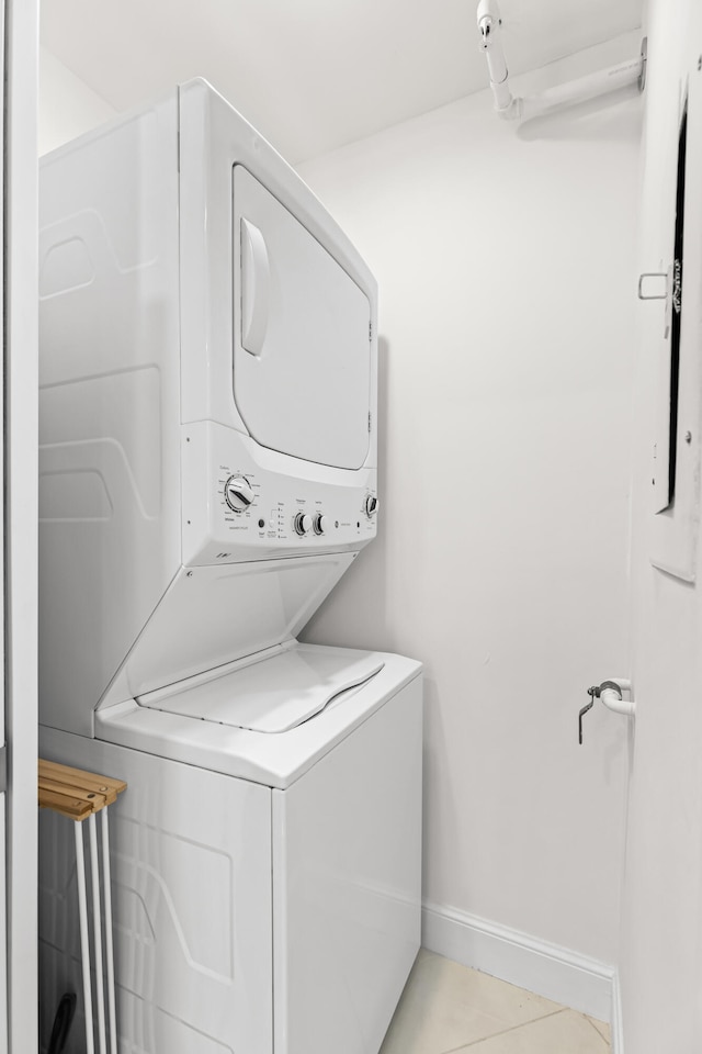 laundry room featuring light tile patterned flooring and stacked washing maching and dryer