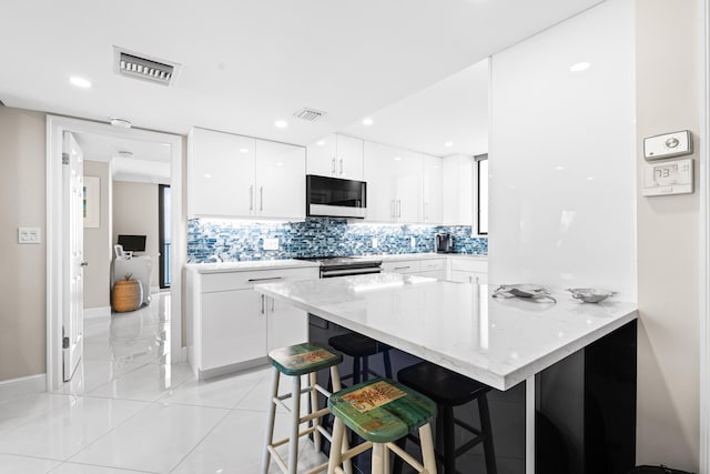 kitchen featuring backsplash, a breakfast bar area, and white cabinets