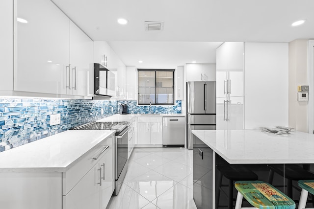 kitchen featuring sink, stainless steel appliances, light stone counters, white cabinets, and decorative backsplash