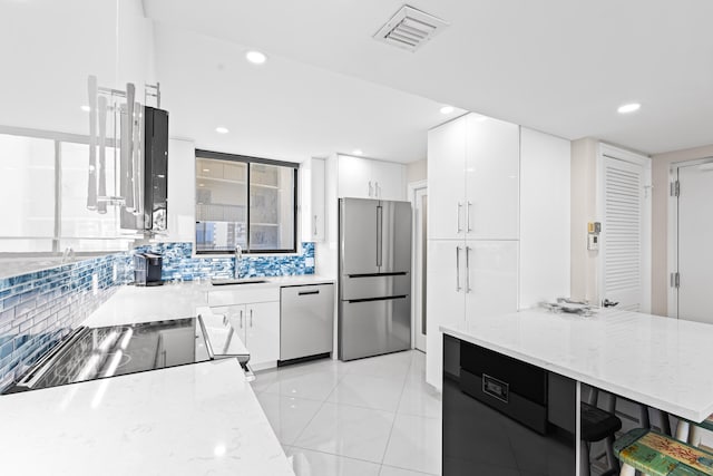 kitchen with stainless steel appliances, sink, white cabinets, and light stone counters