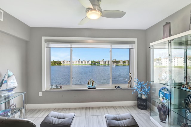 sitting room featuring a water view and ceiling fan