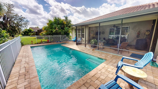 view of swimming pool featuring a sunroom, ceiling fan, and a patio area