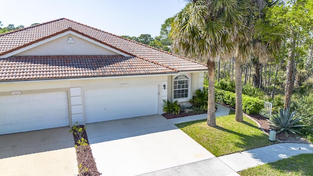 mediterranean / spanish home with a tiled roof, a garage, driveway, and stucco siding