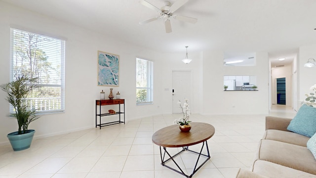 living area with light tile patterned floors, a ceiling fan, and baseboards