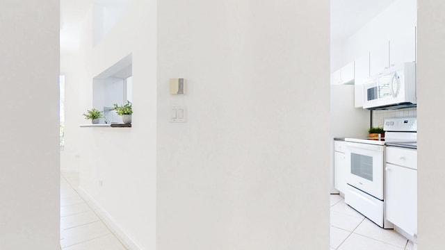 kitchen with light tile patterned floors, white appliances, tasteful backsplash, and white cabinets