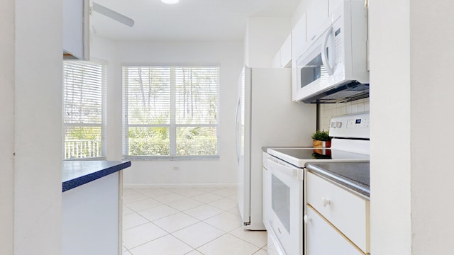 kitchen featuring baseboards, decorative backsplash, light tile patterned flooring, white appliances, and white cabinetry