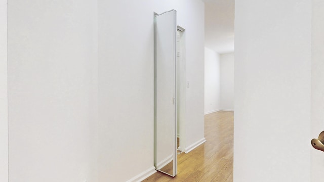 corridor with baseboards and light wood-style floors