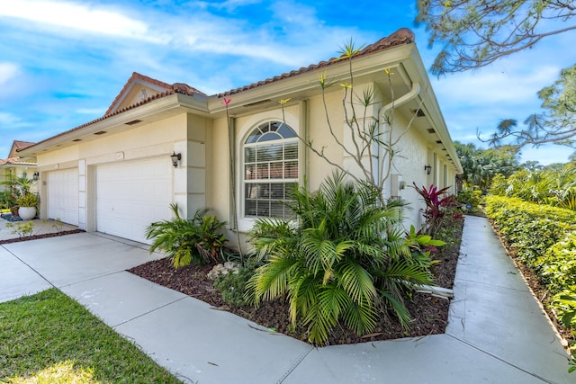 view of side of home featuring stucco siding, concrete driveway, and an attached garage