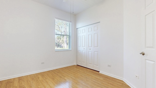 unfurnished bedroom with a closet, baseboards, and light wood finished floors