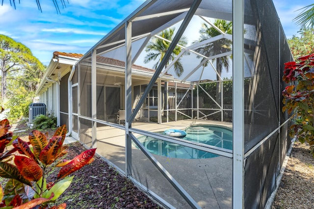 outdoor pool with glass enclosure, a patio area, and central AC