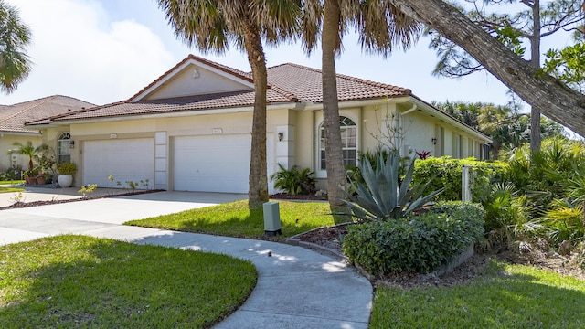 mediterranean / spanish house featuring a front yard, stucco siding, concrete driveway, a garage, and a tile roof