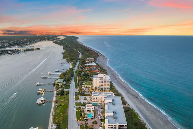 aerial view at dusk with a water view and a beach view