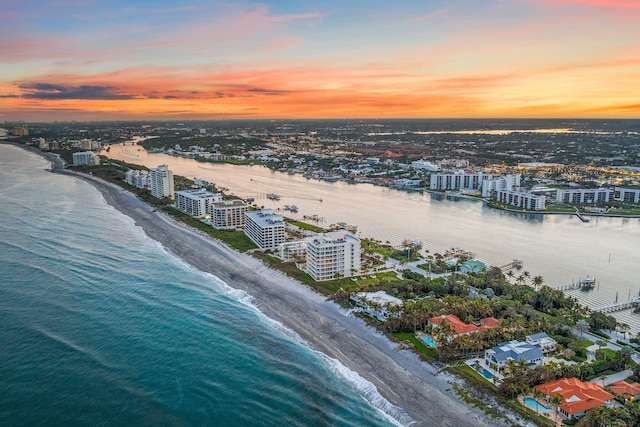 aerial view at dusk with a water view and a view of the beach