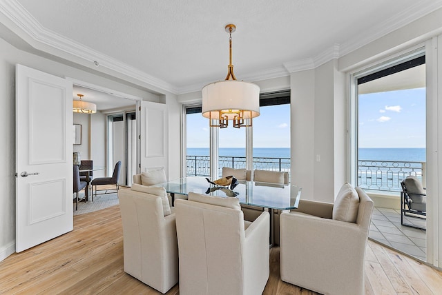 dining area with a water view, hardwood / wood-style floors, and a notable chandelier