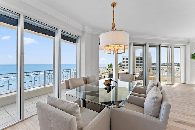 dining room with ornamental molding, a water view, a notable chandelier, and light hardwood / wood-style flooring