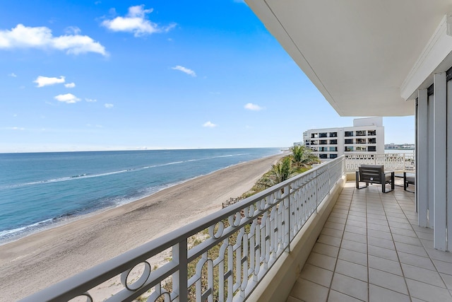 balcony with a water view and a view of the beach