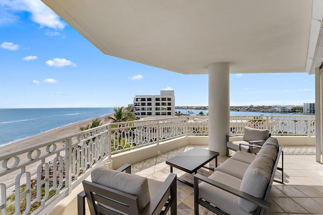 balcony with a water view, an outdoor living space, and a beach view