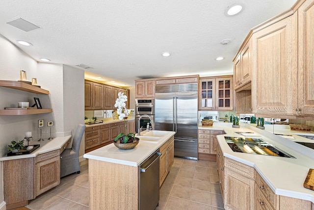 kitchen featuring stainless steel appliances, an island with sink, light tile patterned floors, and a textured ceiling