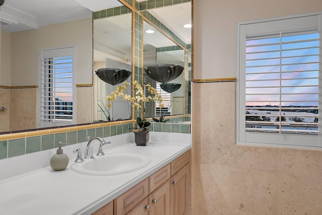 bathroom with tile walls, vanity, crown molding, and a healthy amount of sunlight