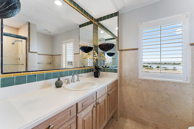 bathroom featuring a shower with door, vanity, ornamental molding, and tile walls