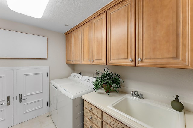 clothes washing area with sink, cabinets, washer and clothes dryer, light tile patterned floors, and a textured ceiling