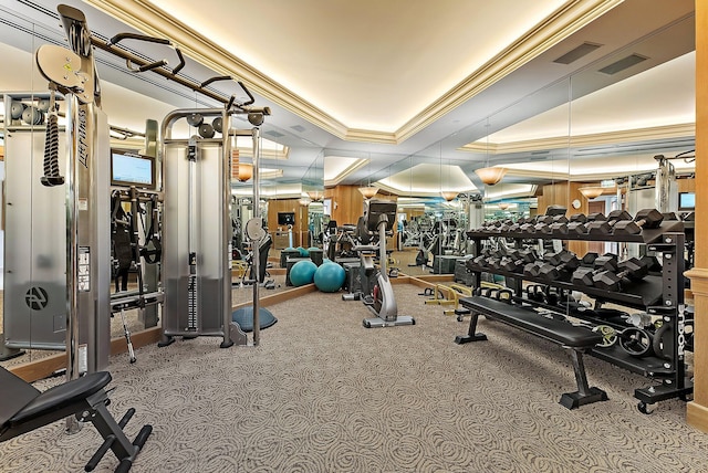 workout area featuring a tray ceiling and ornamental molding