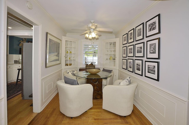 dining area with wainscoting, ornamental molding, and light wood-type flooring