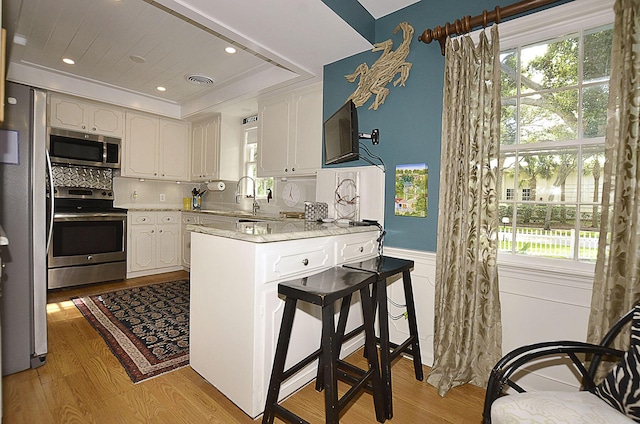 kitchen featuring a peninsula, light wood-style floors, plenty of natural light, and appliances with stainless steel finishes