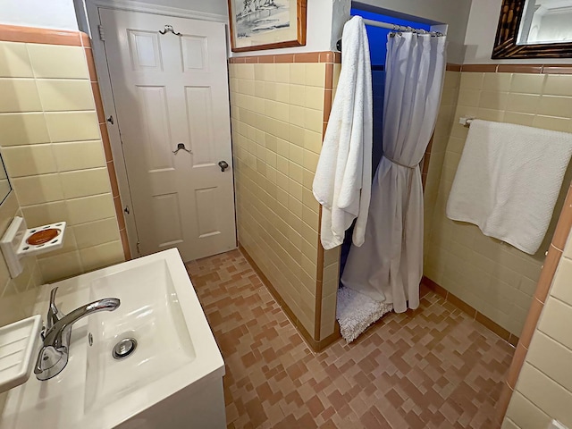 bathroom with a wainscoted wall, a shower with shower curtain, vanity, and tile walls