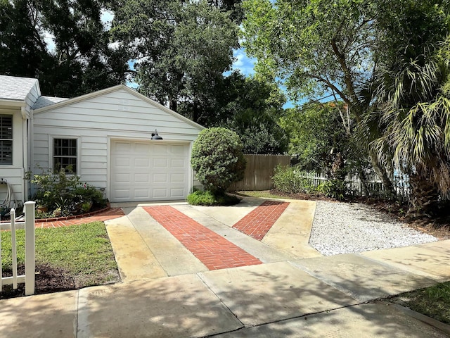 garage with concrete driveway and fence