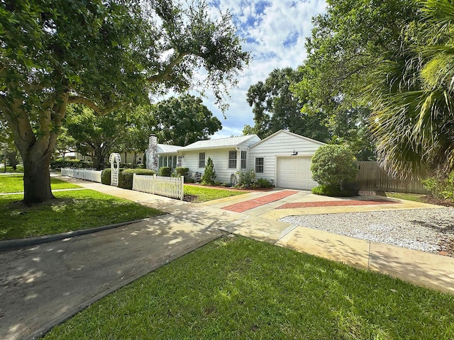 view of front of house featuring a garage, driveway, a front lawn, and a fenced front yard