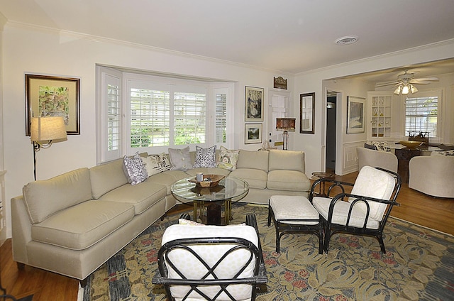 living area featuring ornamental molding, visible vents, ceiling fan, and wood finished floors