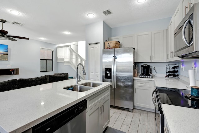 kitchen with sink, a textured ceiling, ceiling fan, stainless steel appliances, and white cabinets