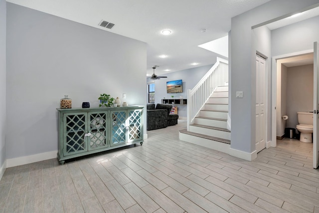 stairway with hardwood / wood-style floors and ceiling fan