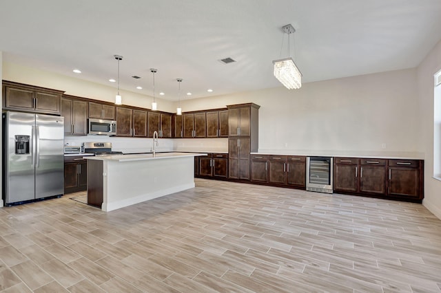 kitchen with wine cooler, stainless steel appliances, sink, and hanging light fixtures