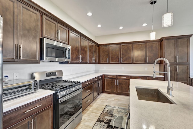 kitchen featuring pendant lighting, sink, dark brown cabinets, and stainless steel appliances