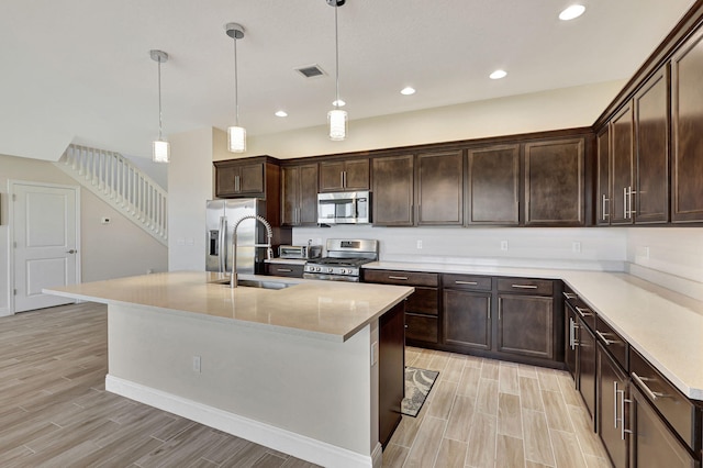 kitchen with pendant lighting, sink, a center island with sink, and appliances with stainless steel finishes