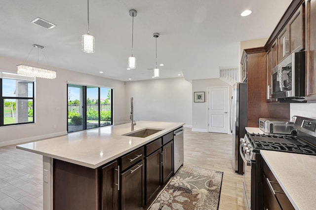 kitchen with pendant lighting, sink, a kitchen island with sink, dark brown cabinetry, and stainless steel appliances