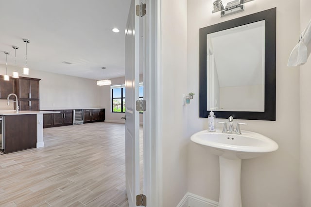 bathroom with wine cooler, sink, and hardwood / wood-style flooring