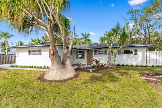 ranch-style home with fence, a front yard, and stucco siding
