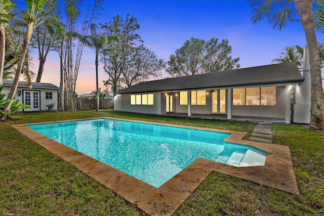 pool at dusk featuring an outbuilding and a yard